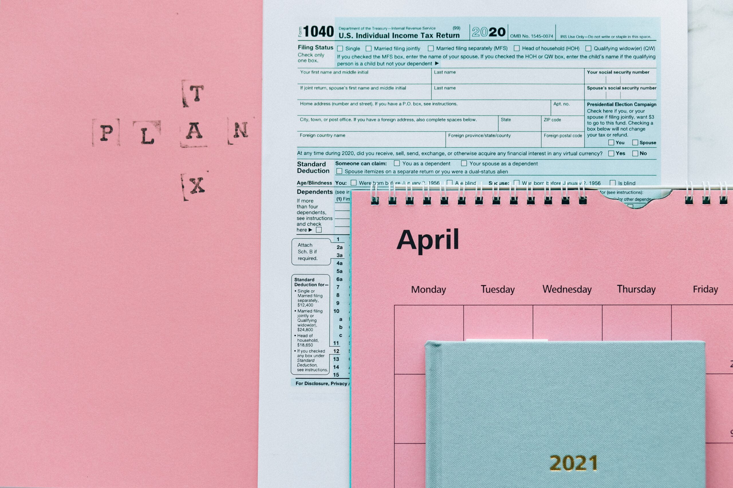 Image showing a tax return form and 2021 planner on pink surface
